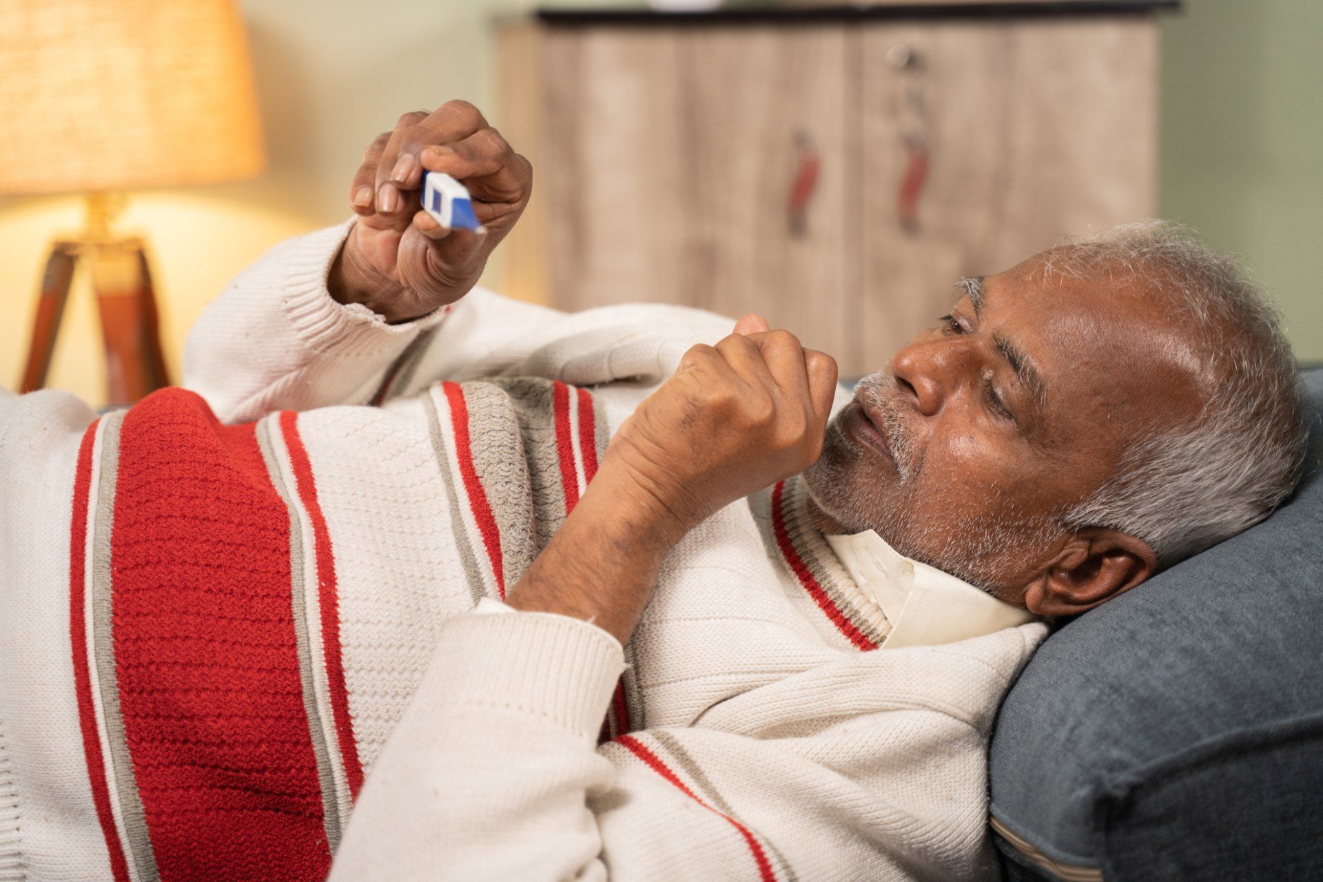 Elderly man coughing and checking his temperature