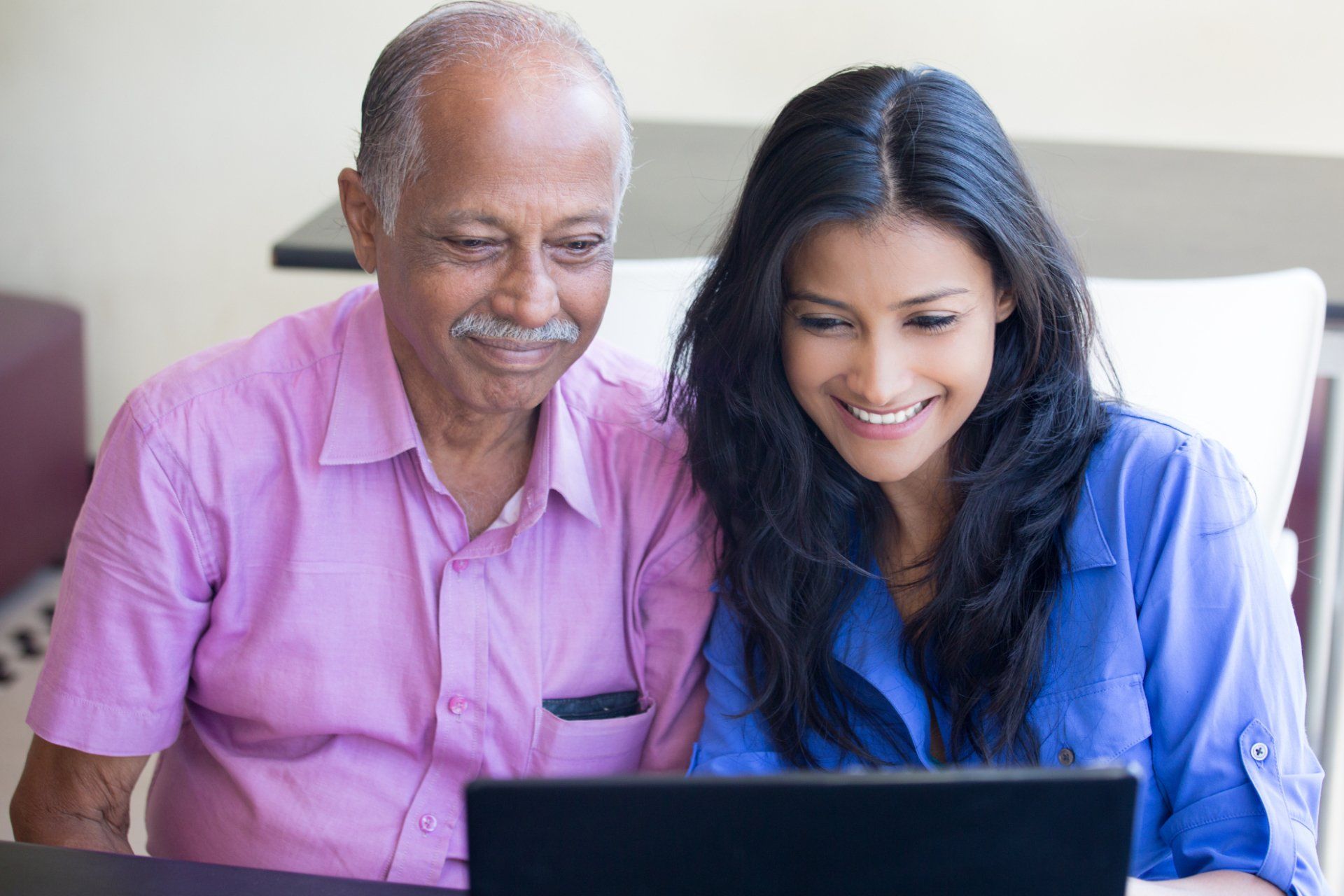 Older father and adult daughter using a laptop